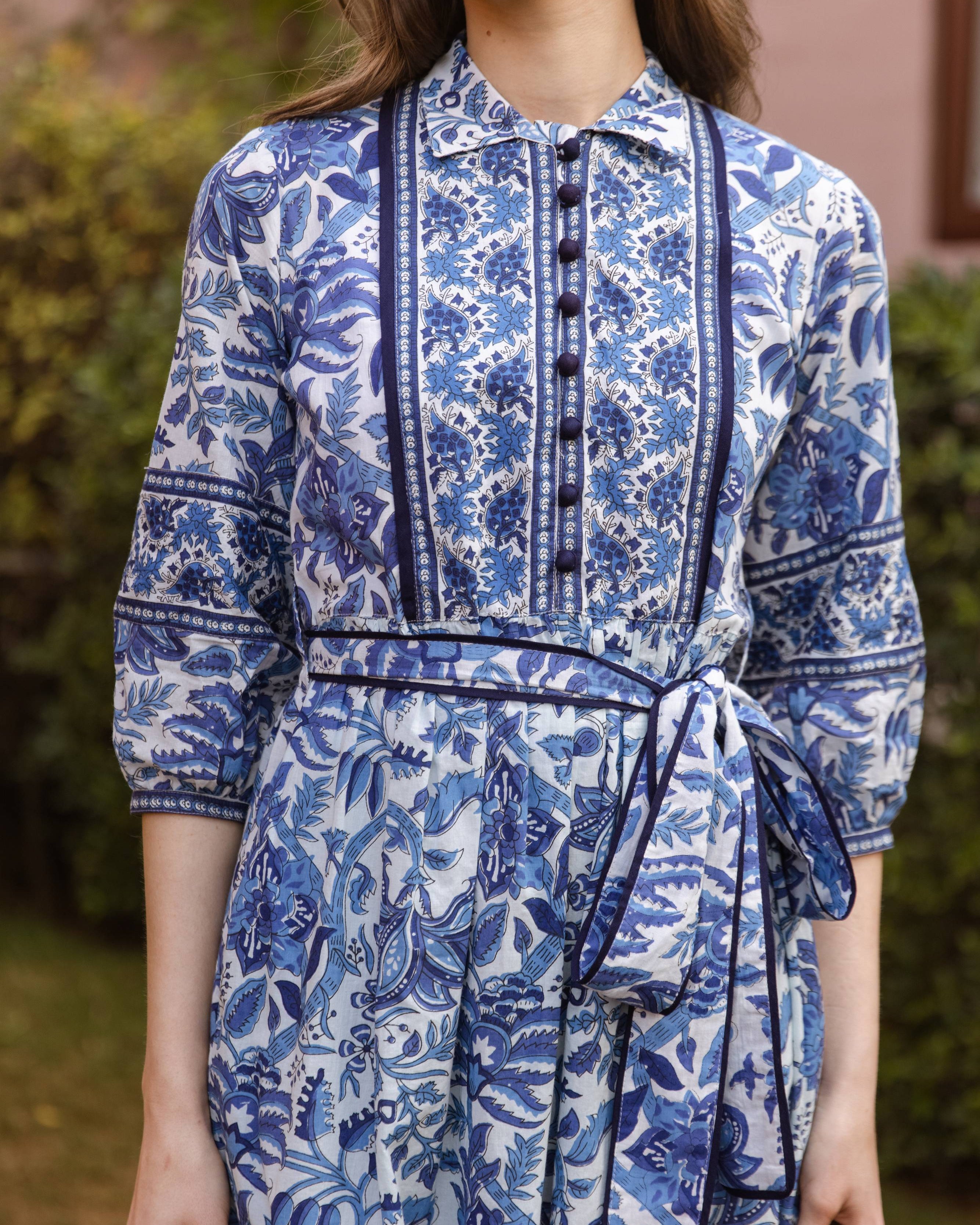 Woman wearing a blue and white floral dress with a blurred background