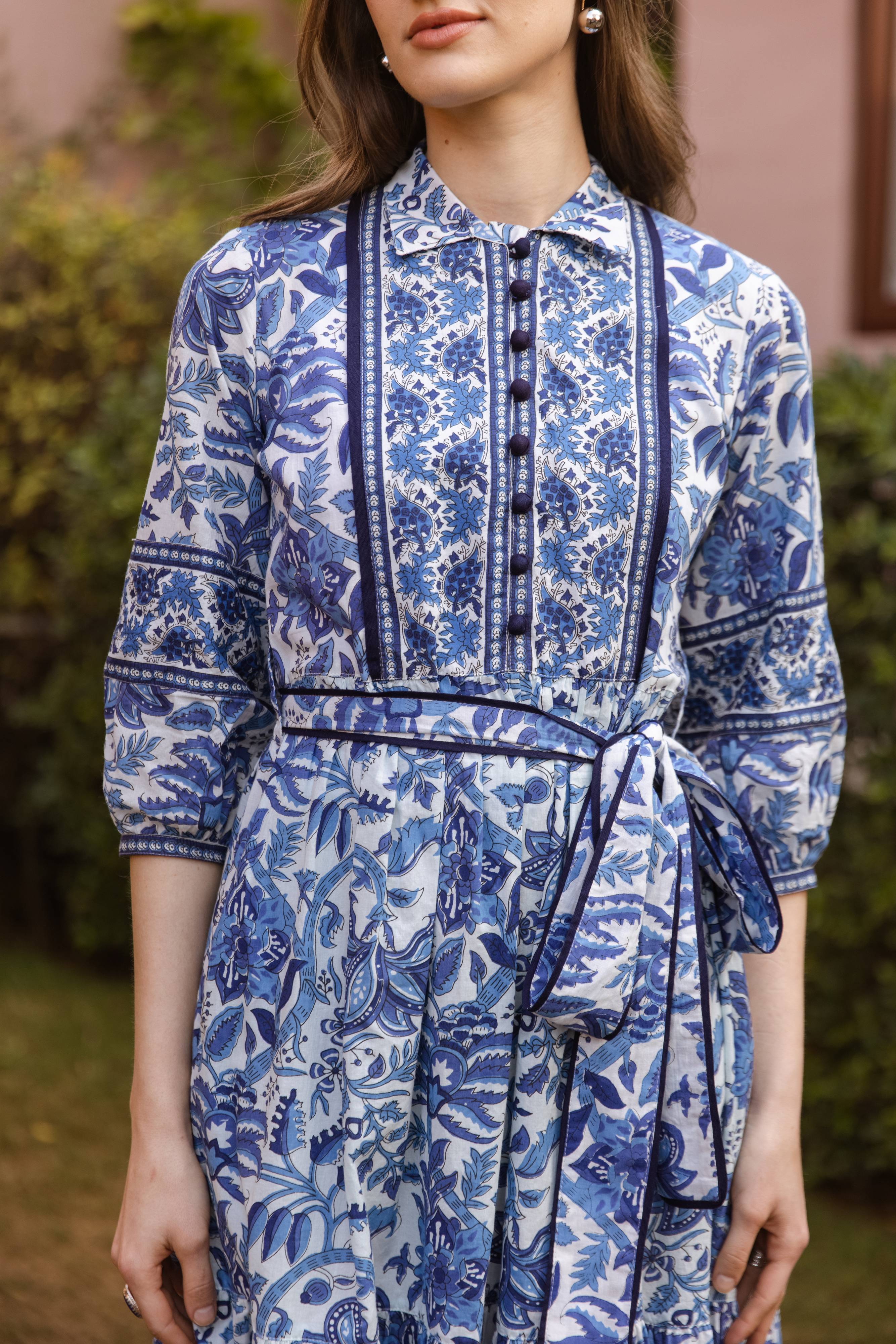 Woman wearing a blue and white floral dress with a blurred background
