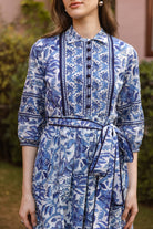 Woman wearing a blue and white floral dress with a blurred background