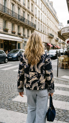 Blue Cat Chaos Jacket in navy and cream abstract cat print, back view showing full print placement and gingham cuffs, worn on a city street